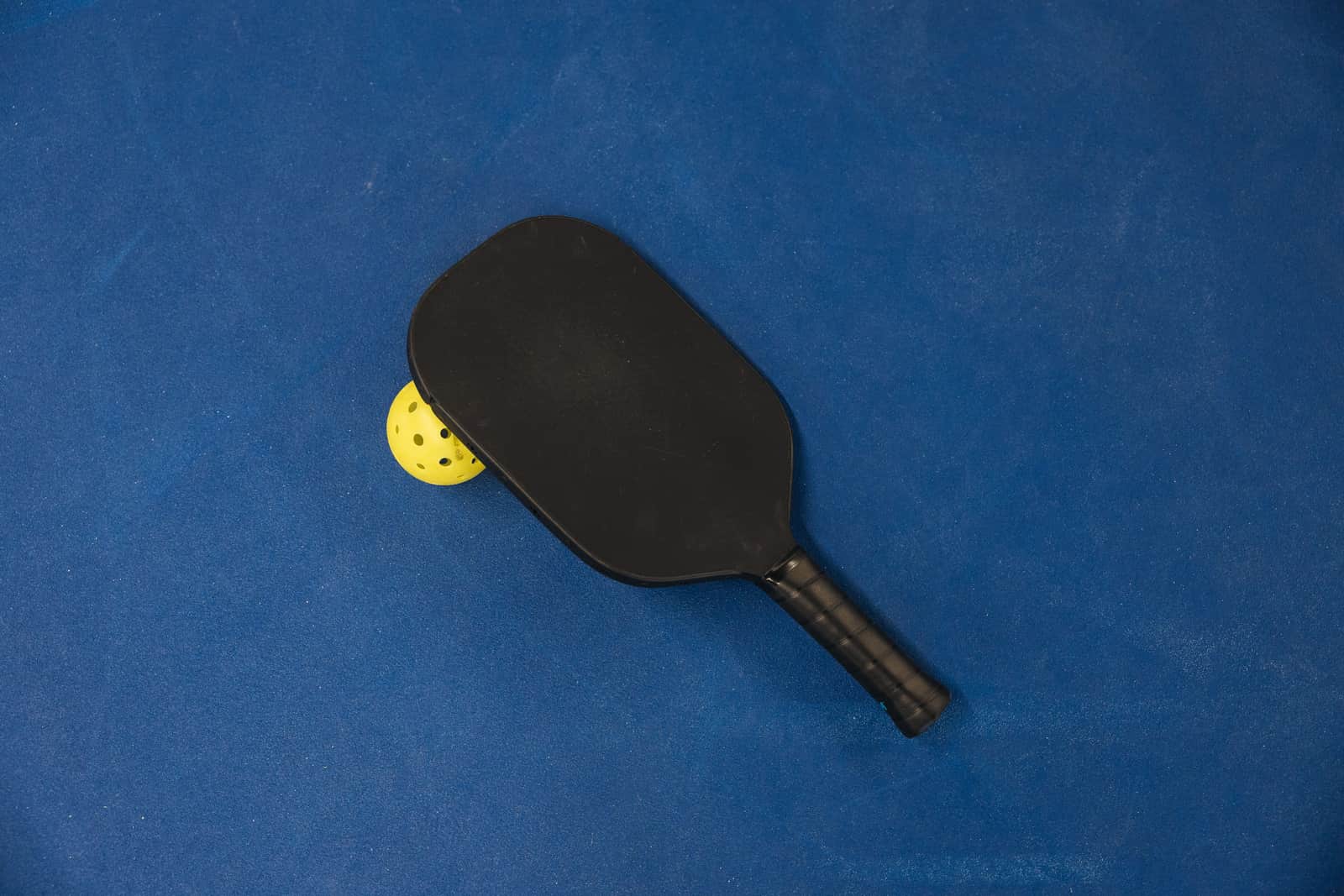 A player's hands resting on a pickleball paddle in soft daylight