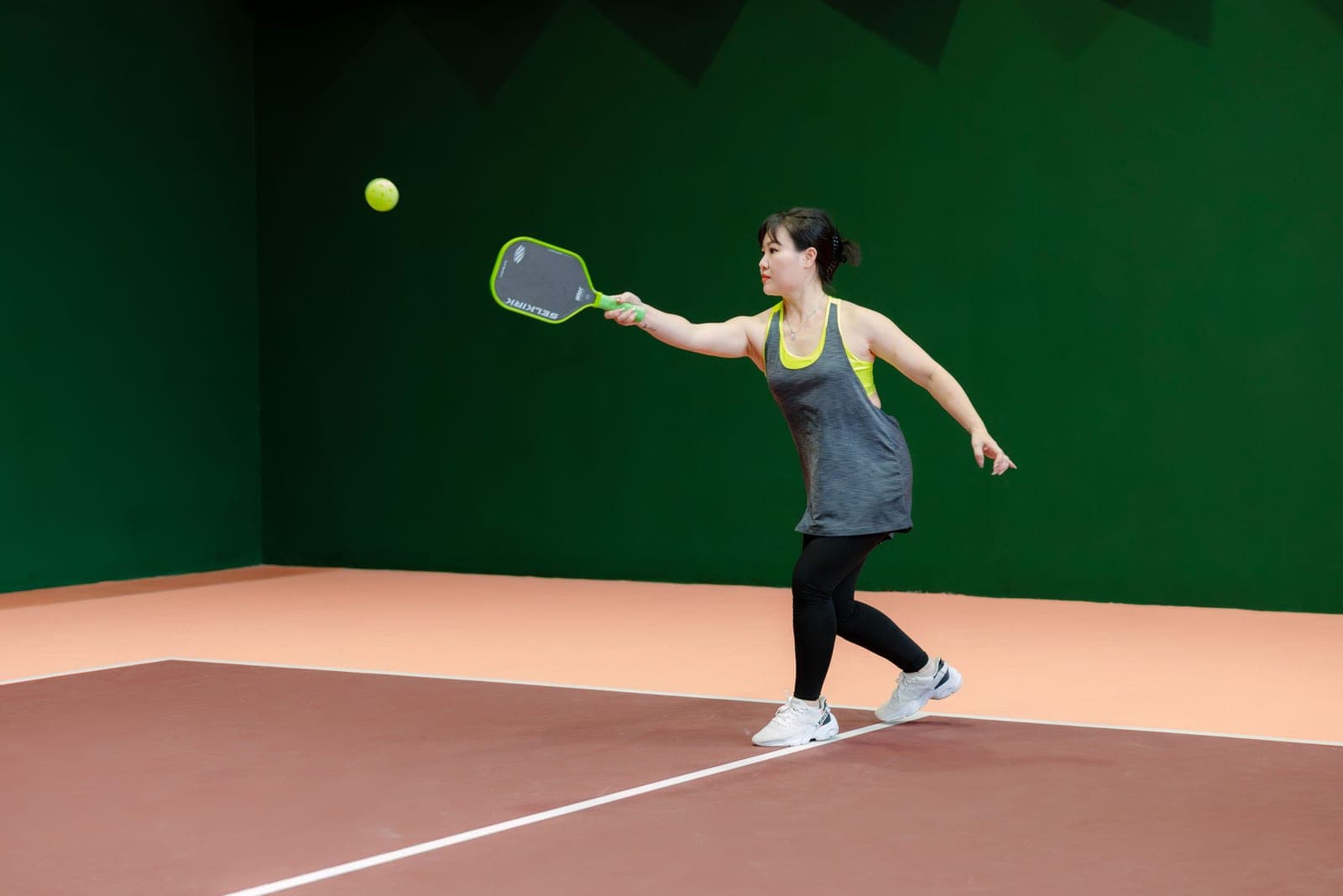 A pickleball player moving on a sunlit court, lower body in focus